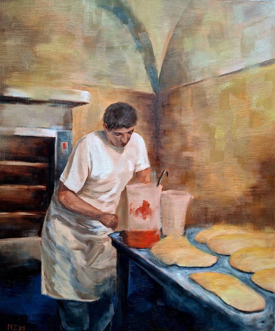 Ein Pizzabäcker in seiner Backstube in Rom. Teige liegen auf dem Tisch, Tomatensoße steht vor ihm.