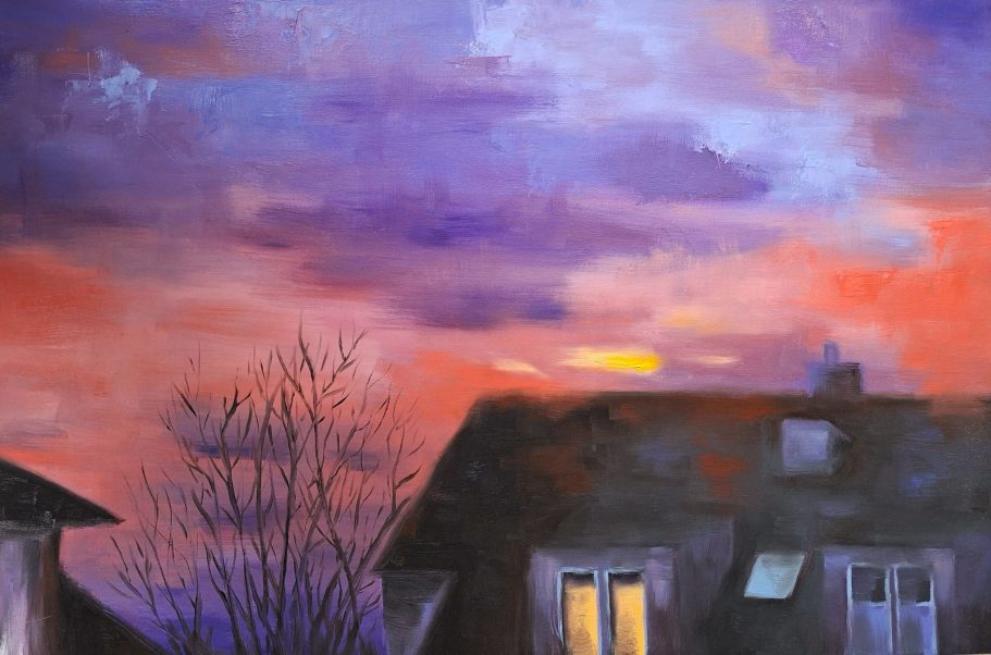 Das Dach eines Wohnhauses und ein Baum ohne Blätte im Abendrot