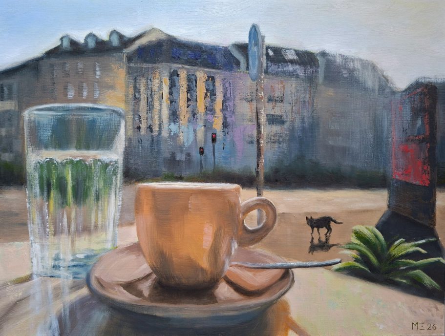 Blick vom Cafétisch auf die Straße. Espresso und Wasser im Vordergrund, Häuser, Straße, Katze im Hintergrund.