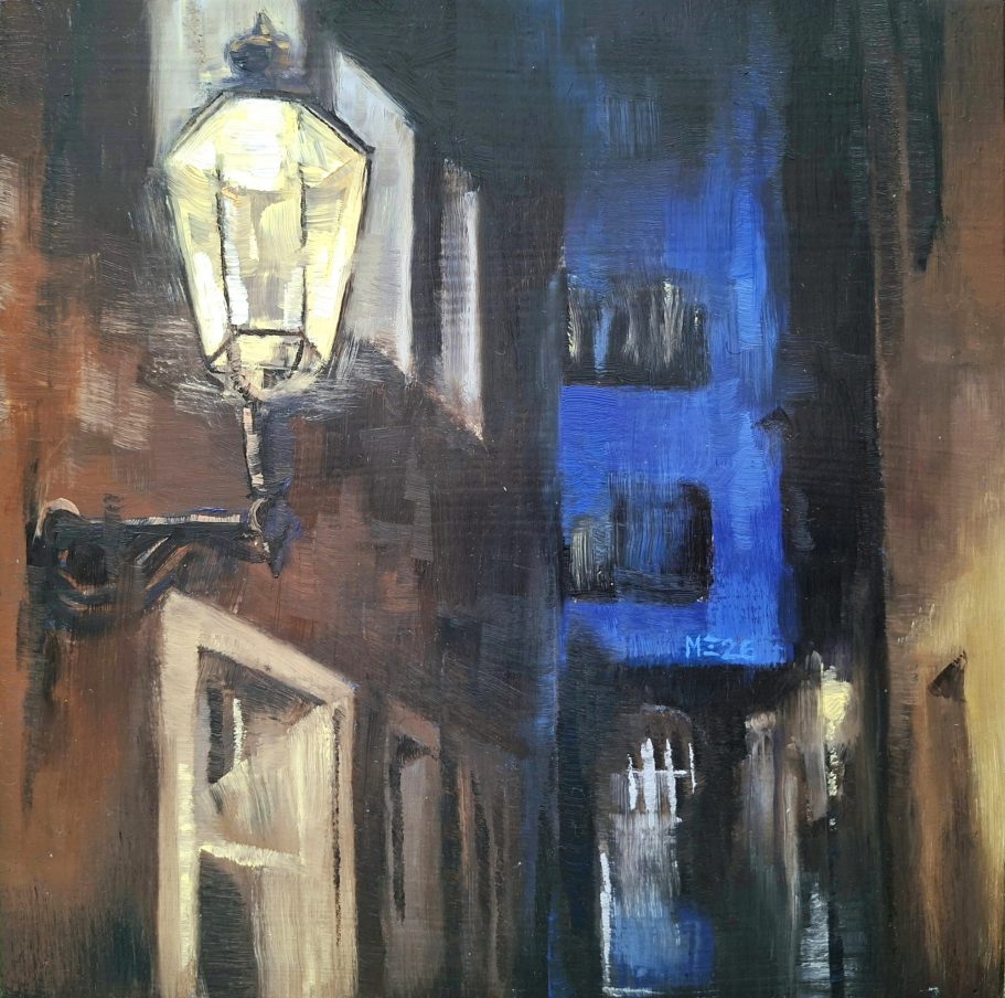 Blick in eine enge Gasse in Köln. Im Vordergrund eine Laterne an einer braunen Hauswand, im Hintergrund ein blaues Haus.